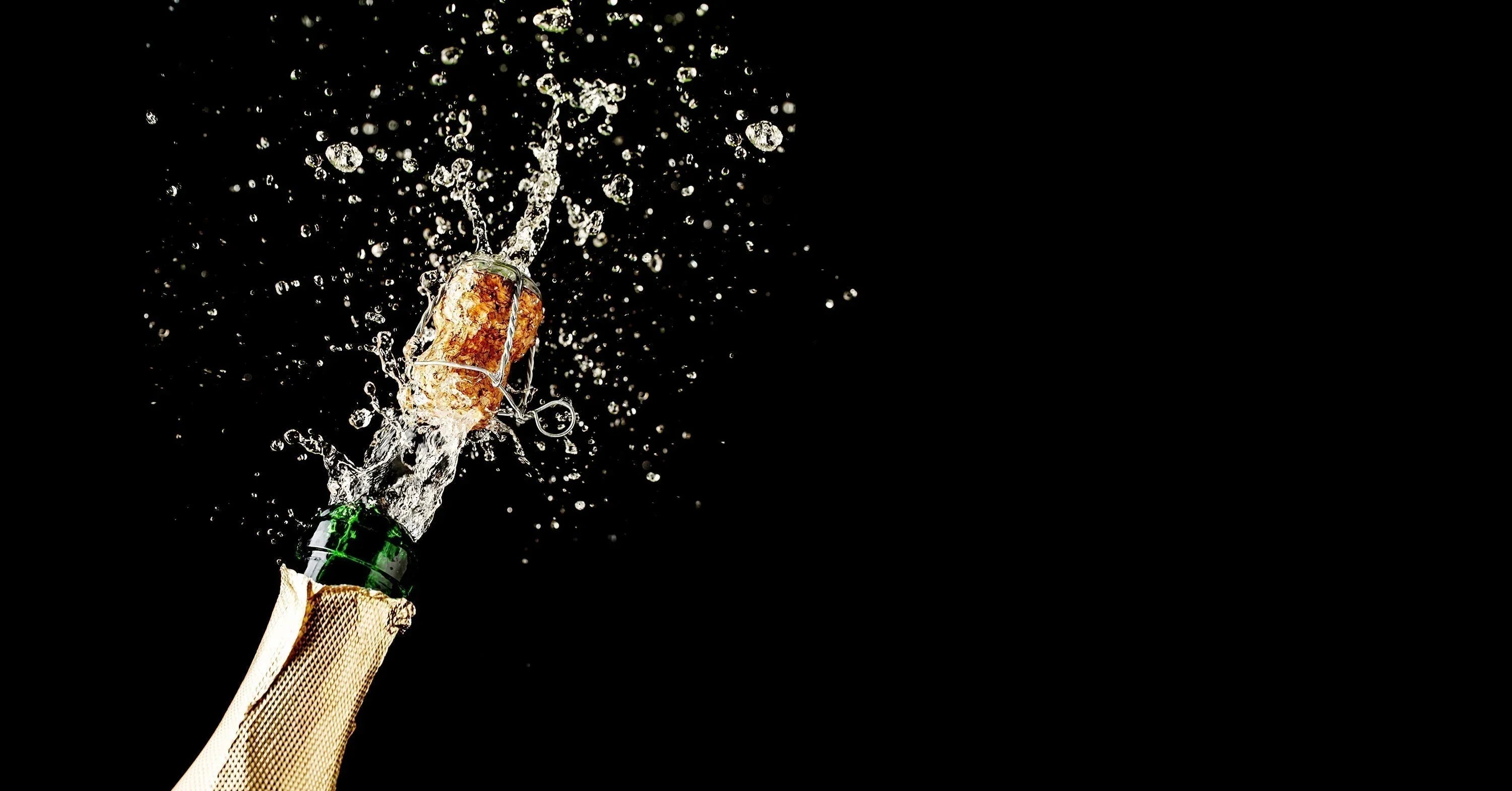 does champagne expire - bottle of champagne popping against a black background