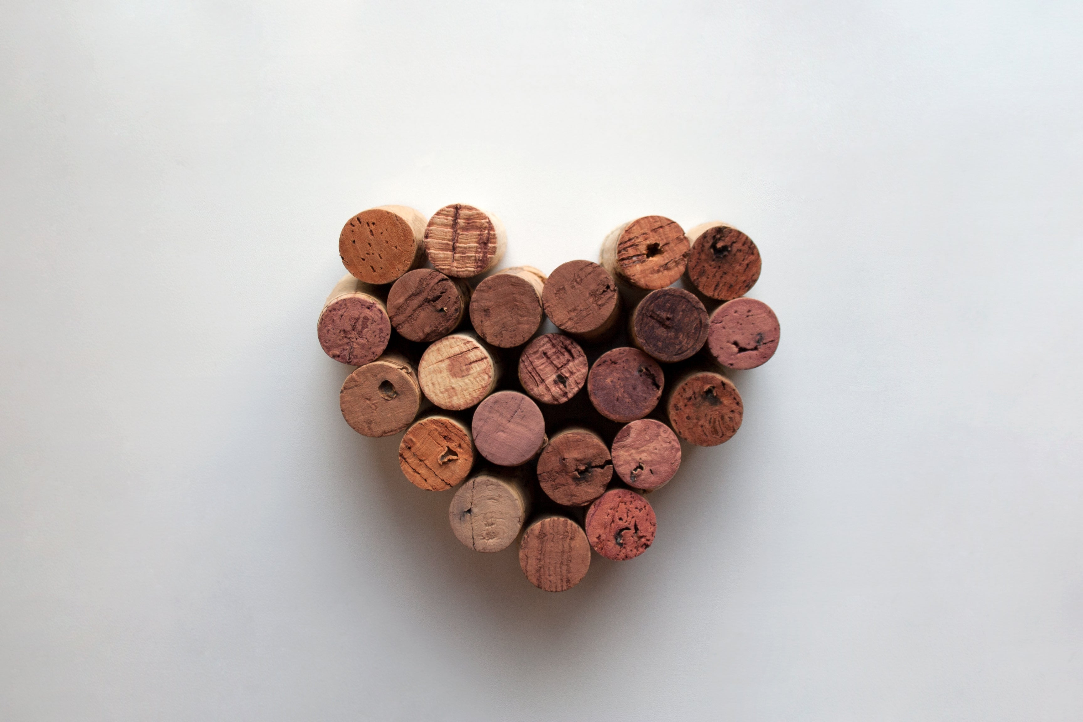 natural wine corks in a love heart shape on white background