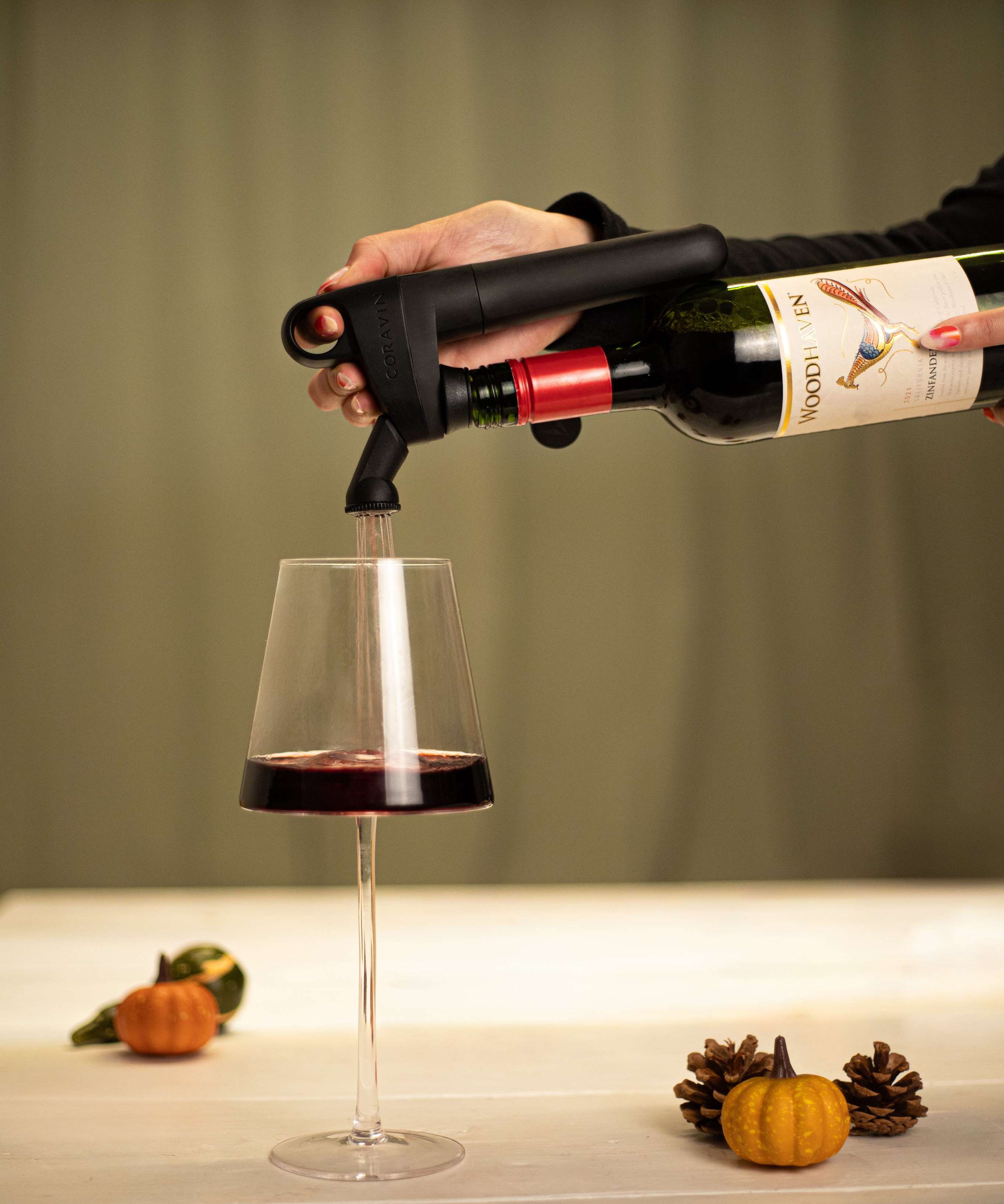 Coravin pivot pouring wine into glass with pumpkin decoration
