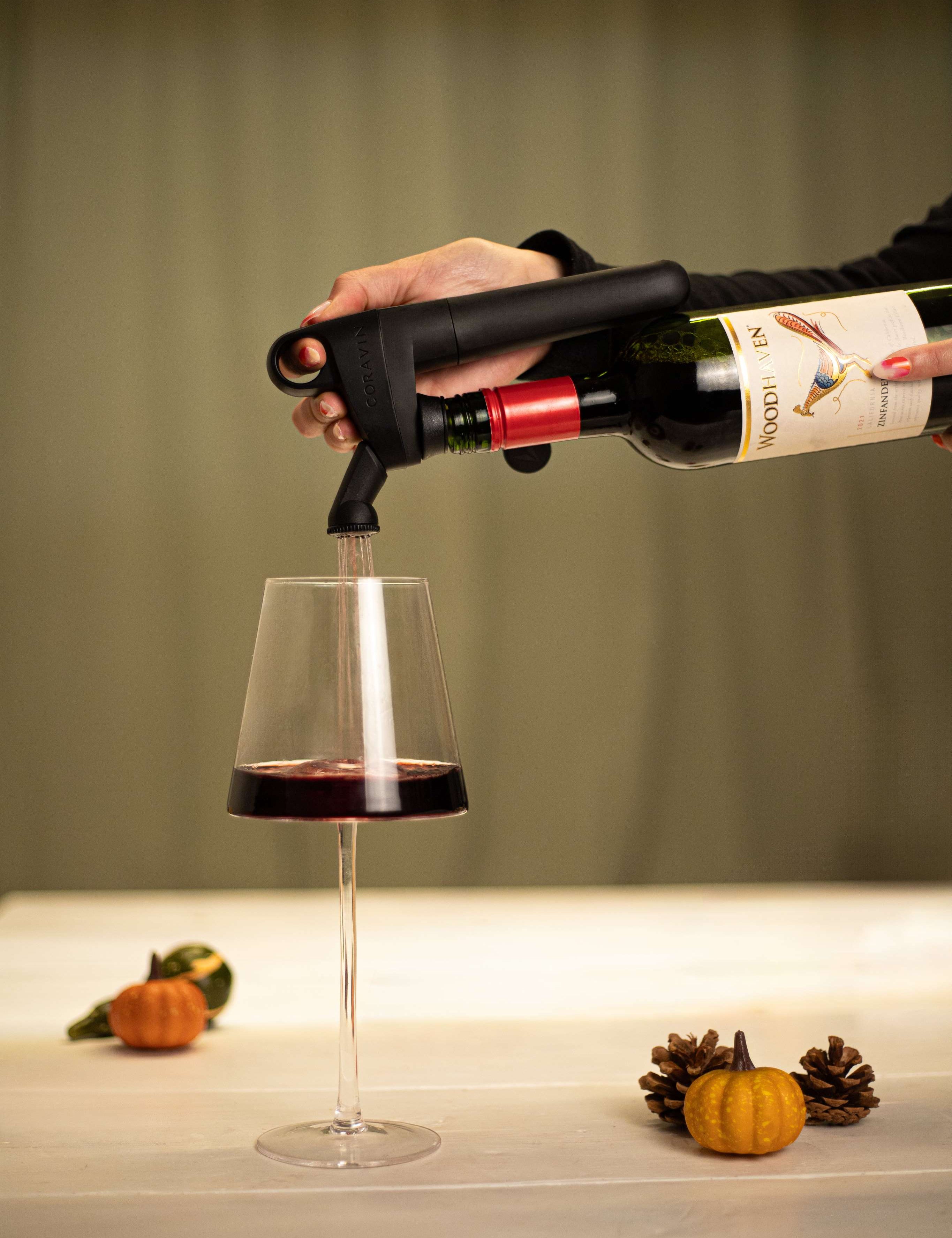 Coravin pivot pouring wine into glass with pumpkin decoration