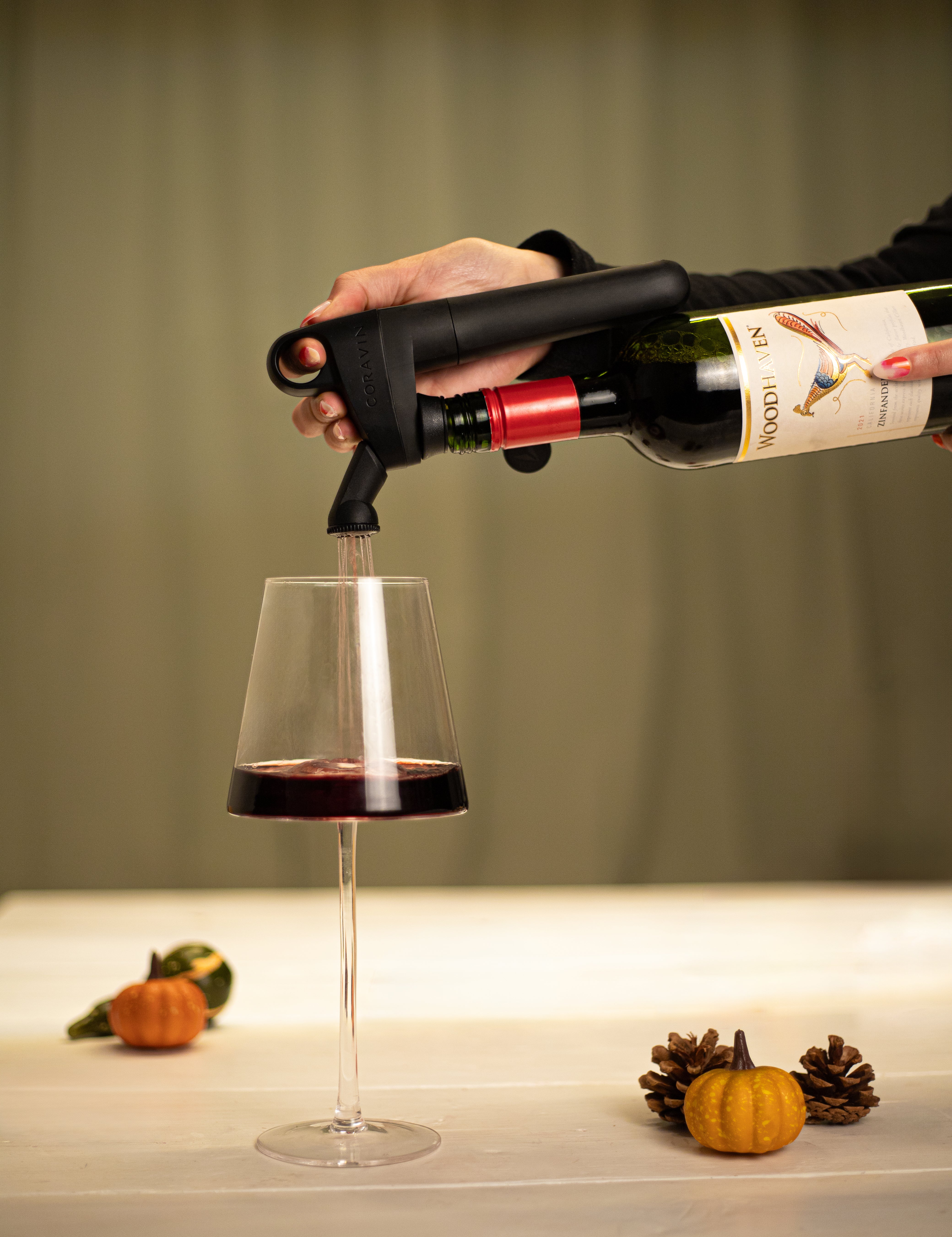 Coravin pivot pouring wine into glass with pumpkin decoration